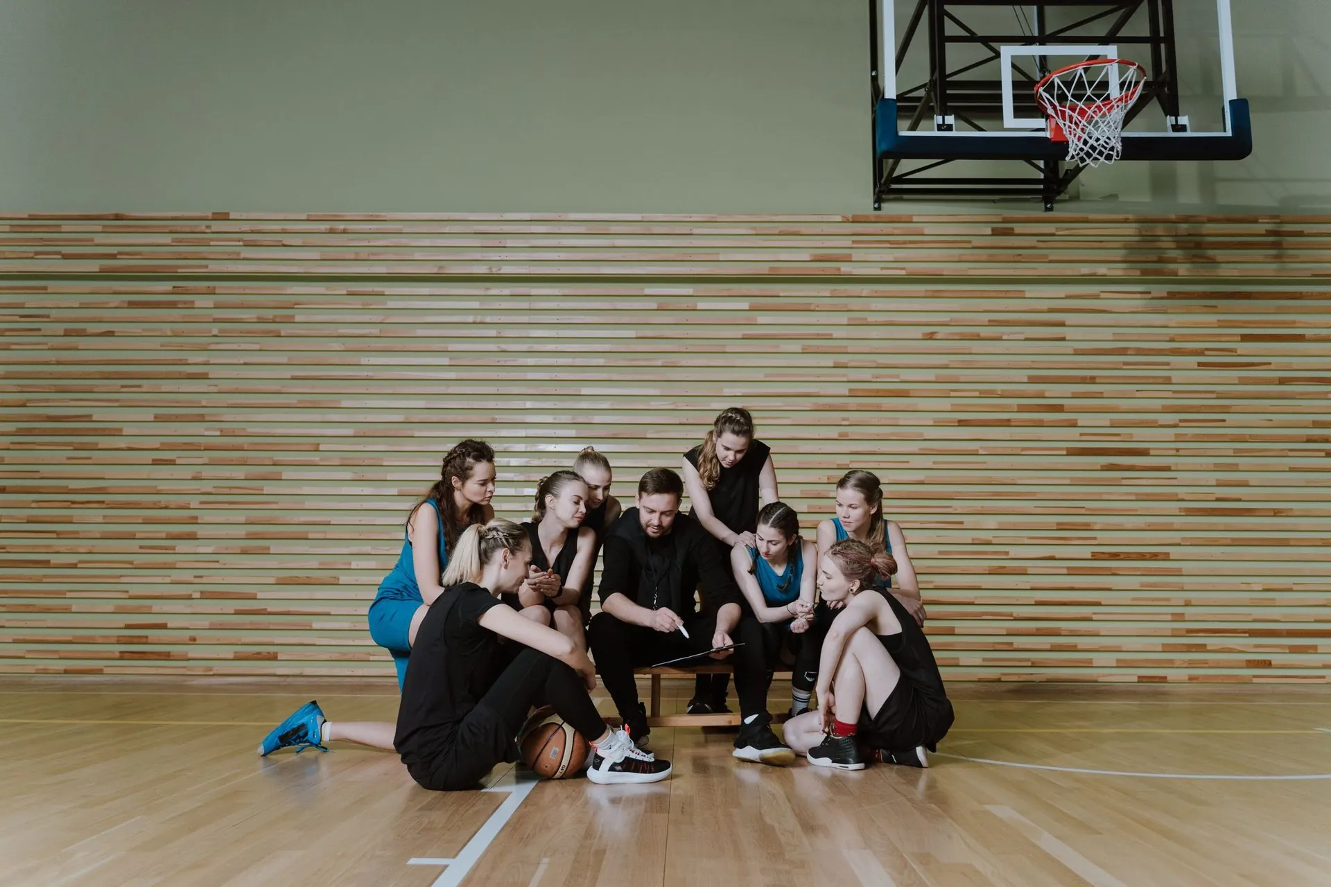Basketball team sitting together on a gym floor, the reality of teamwear for brands