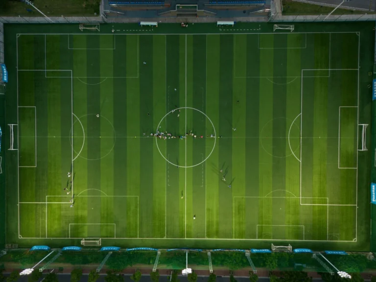Aerial view of a floodlit football pitch, sustainable teamwear for clubs