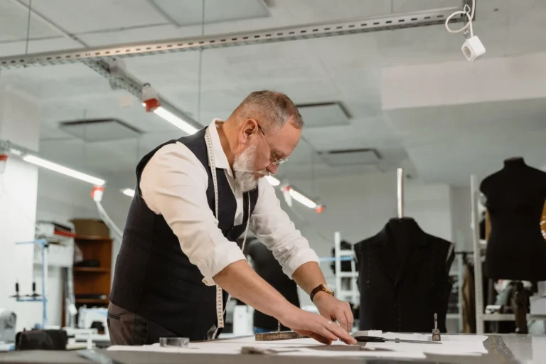 Tailor marking a pattern on a cutting table in a bright workshop, low-MOQ production