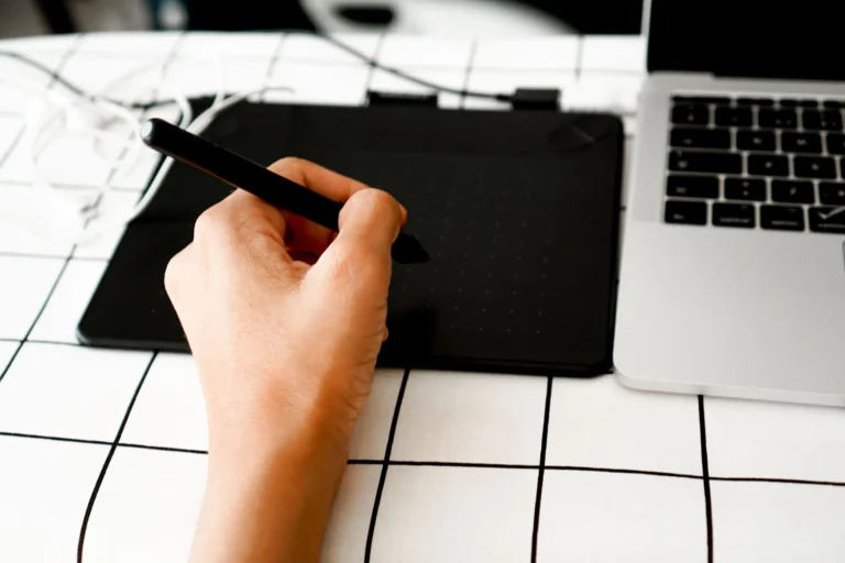 Hand drawing on a graphics tablet beside a laptop, AI design automation in sportswear