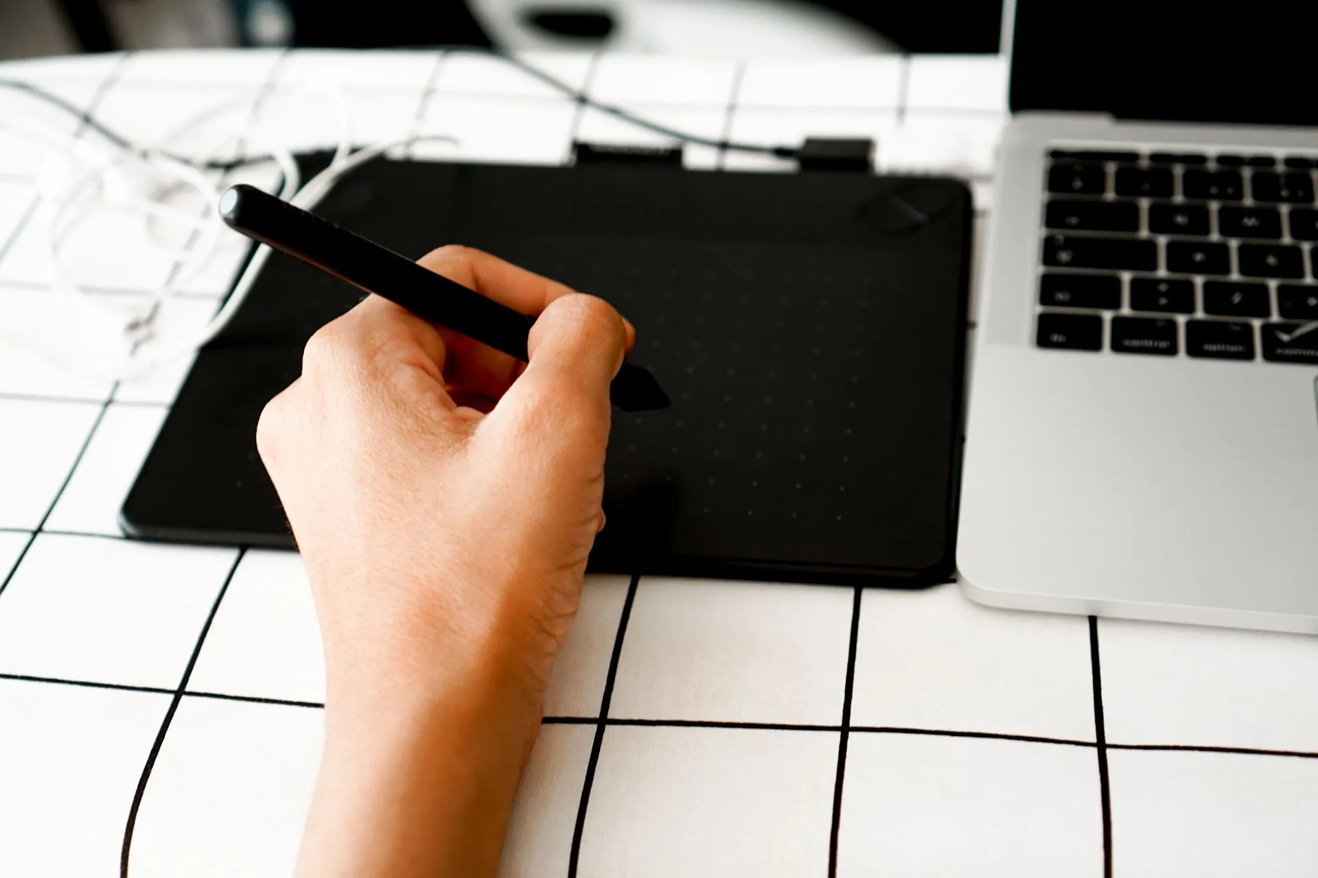 Hand drawing on a graphics tablet beside a laptop, AI design automation in sportswear