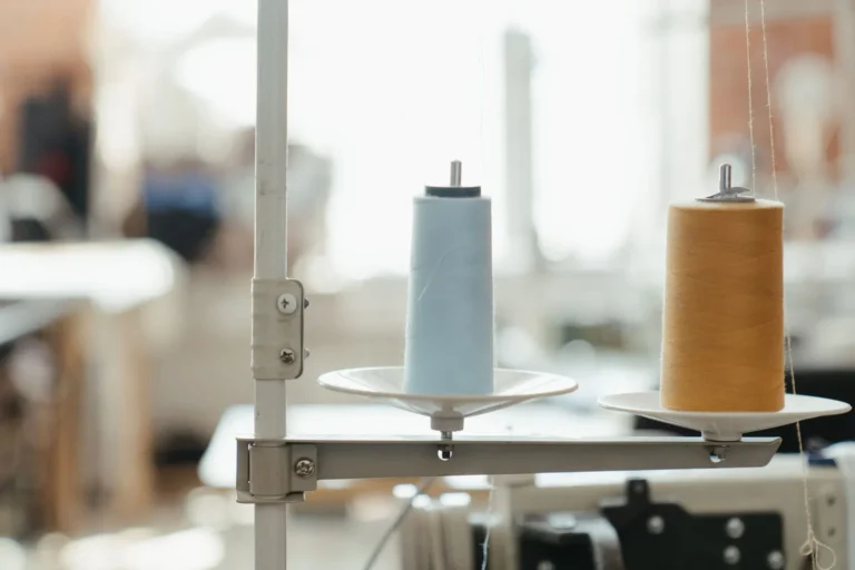 Thread cones on a sewing machine stand in a bright workshop, starting a sportswear business