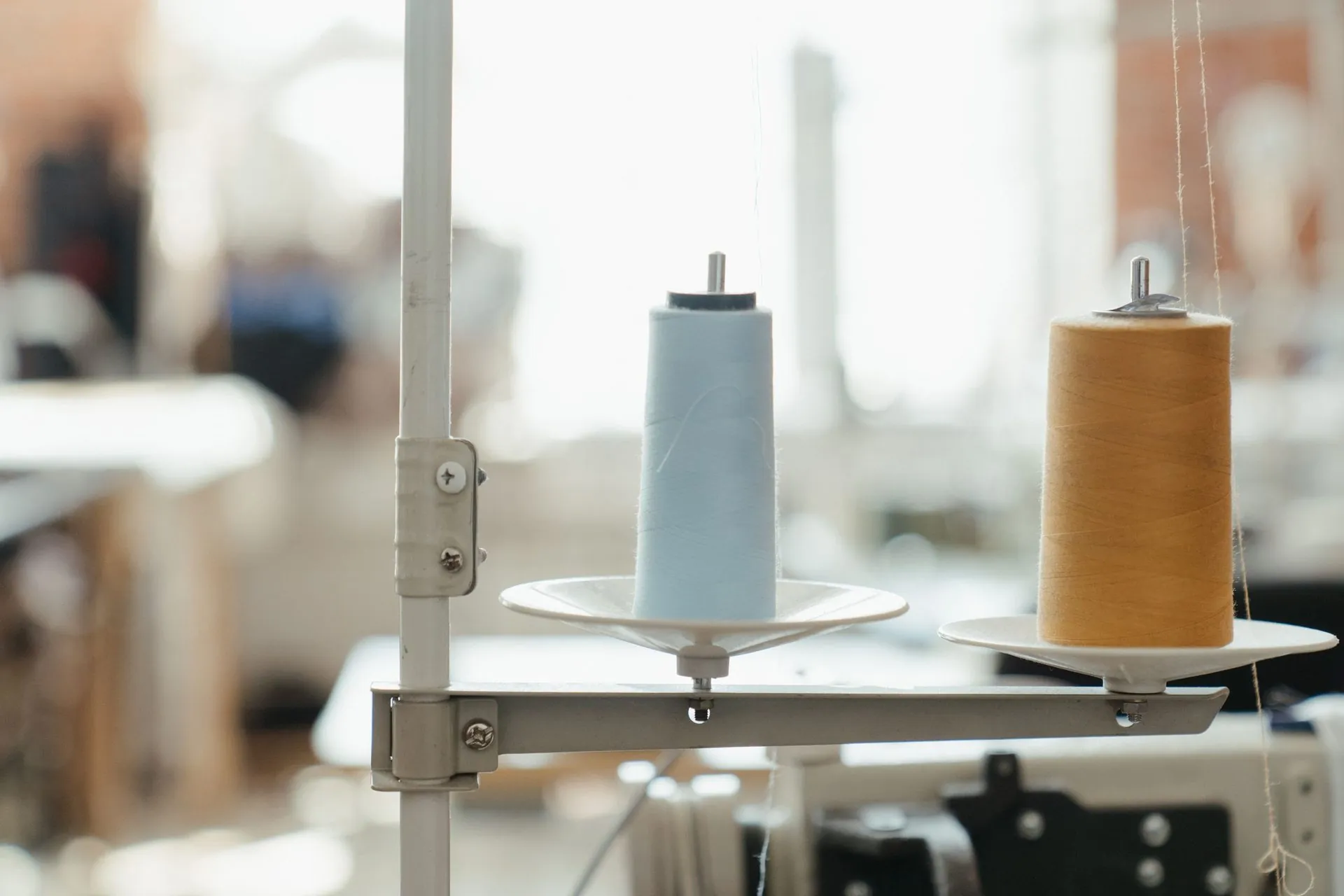 Thread cones on a sewing machine stand in a bright workshop, starting a sportswear business