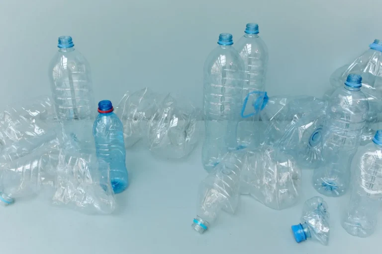 Empty plastic bottles on a pale blue surface, the source of recycled polyester