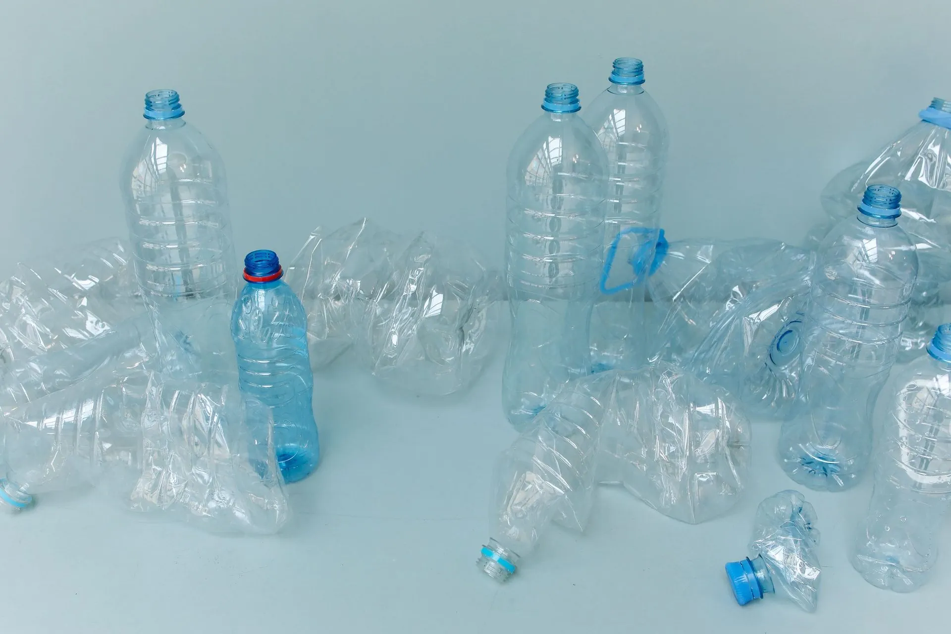 Empty plastic bottles on a pale blue surface, the source of recycled polyester