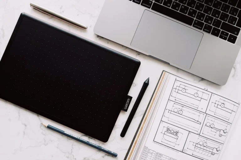 Graphics tablet, laptop and technical sketches on a marble desk, AI sportswear design