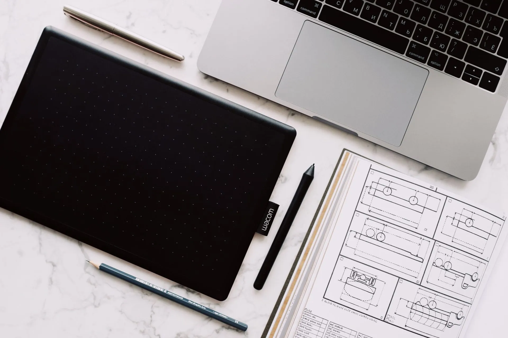 Graphics tablet, laptop and technical sketches on a marble desk, AI sportswear design