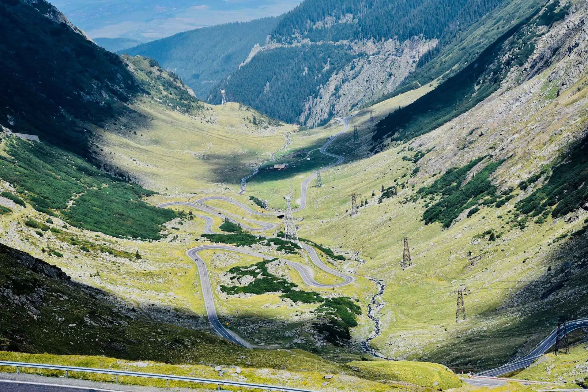 Winding mountain road through a green Carpathian valley in Romania