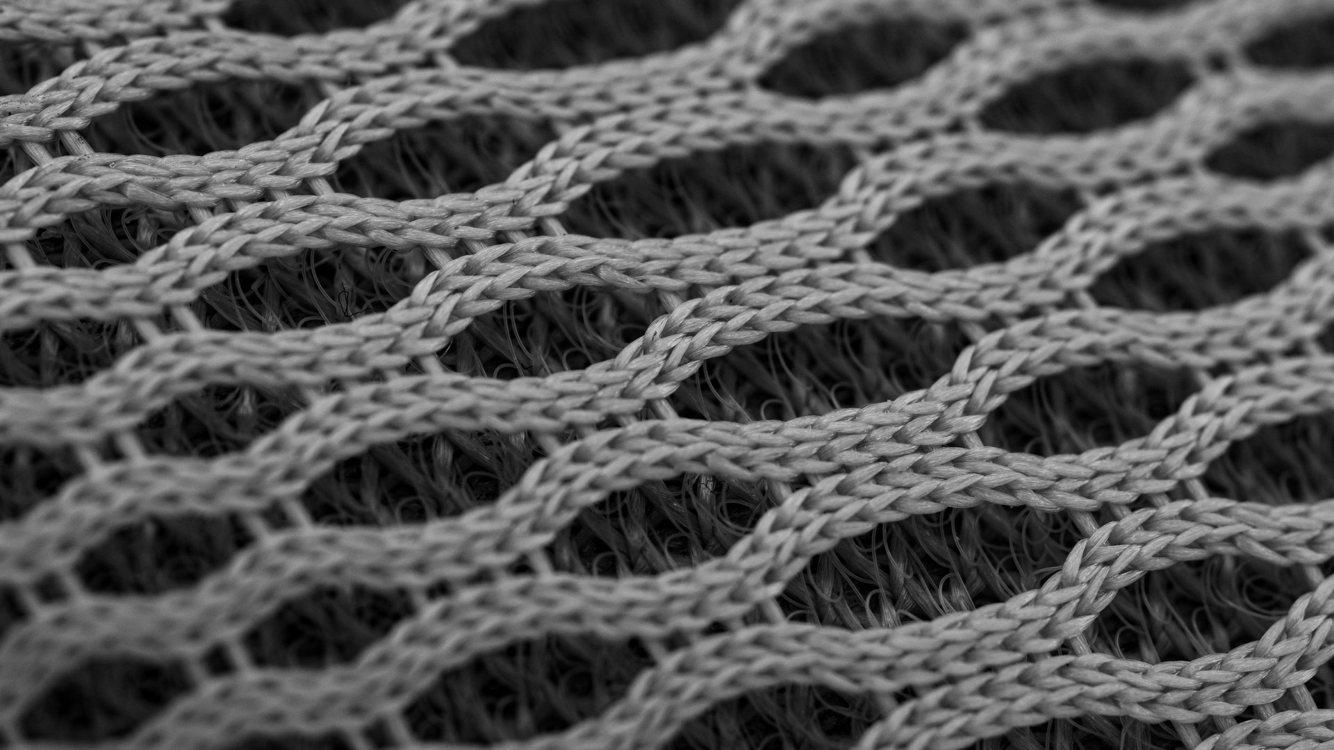 Macro close-up of a grey open knit fabric showing looped yarn structure over a denser layer