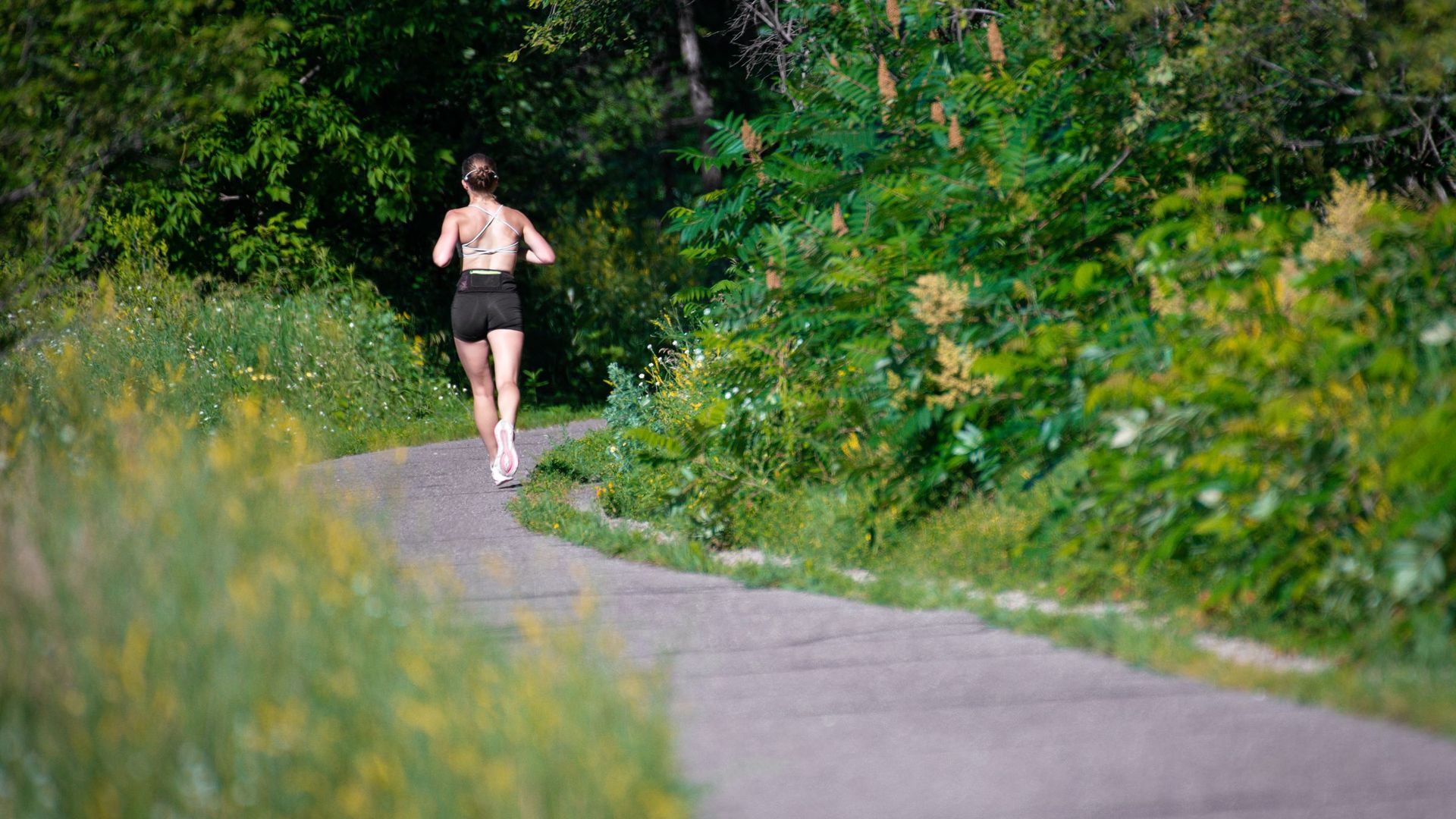 Runner seen from behind on a winding forest path, face out of frame