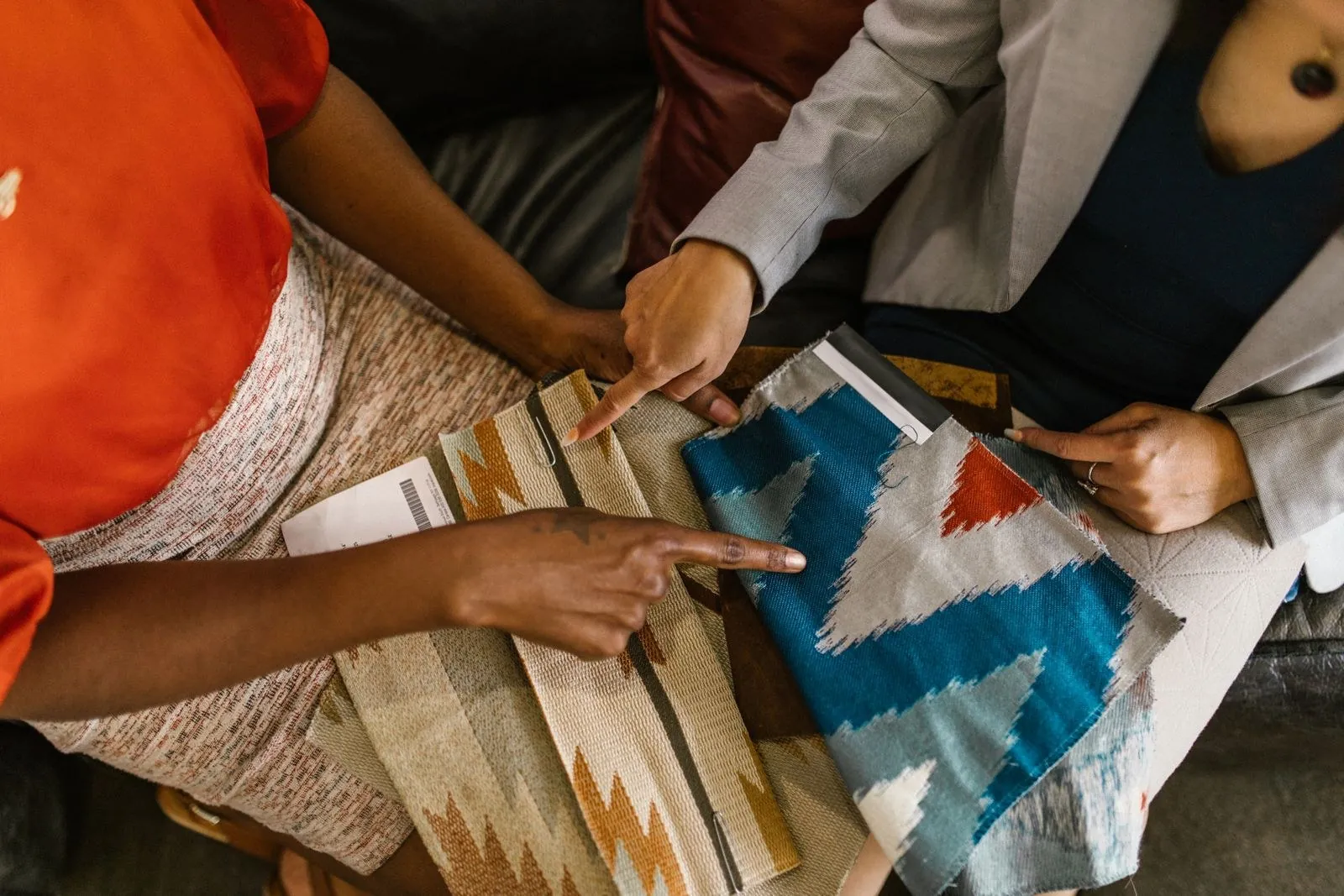 Two people pointing at patterned fabric swatches in blue, orange and beige while choosing colours for a padel apparel range