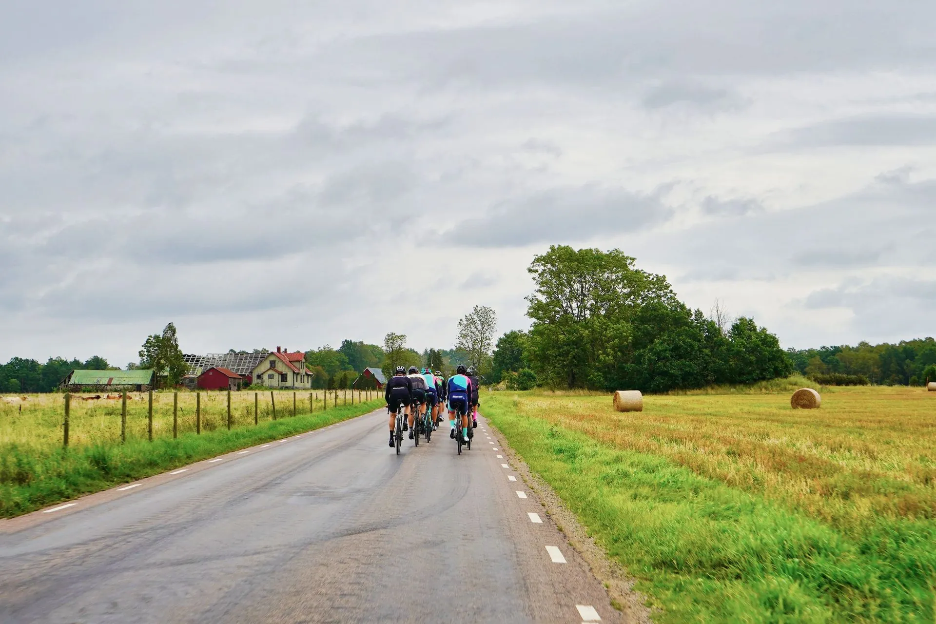 Group of road cyclists riding along a quiet country road in custom cycling kit