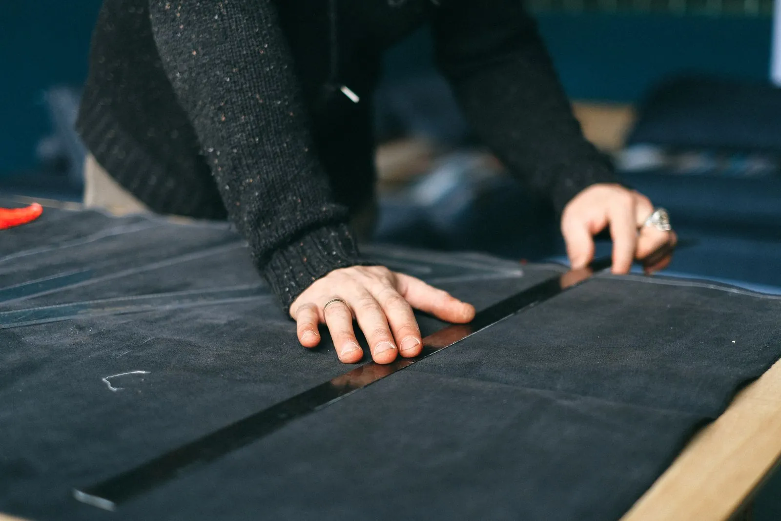 Hands measuring dark fabric on a cutting table, the first step towards a private-label swim rashguard pattern