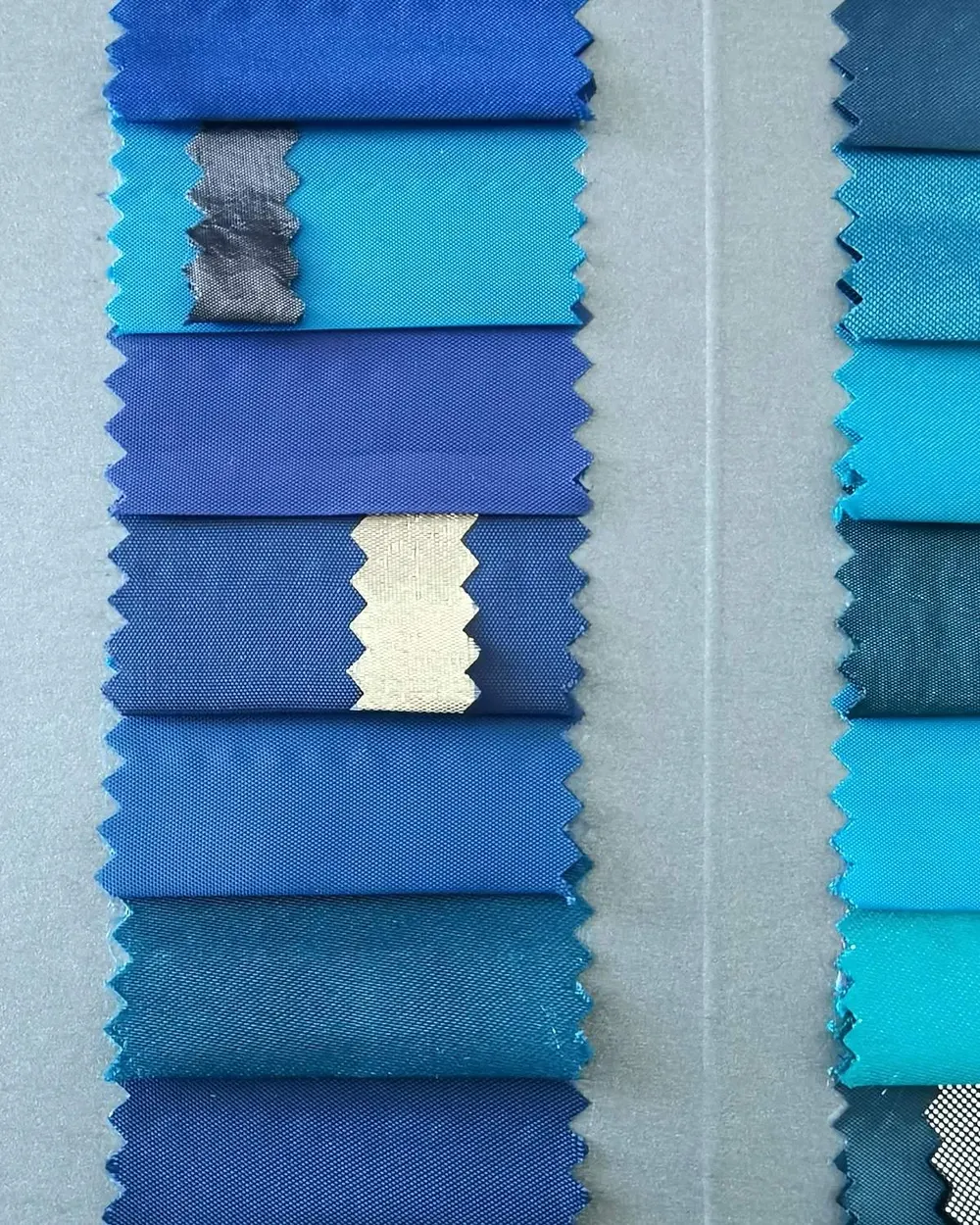 Rows of blue and teal fabric swatches with pinked edges laid out for colour selection
